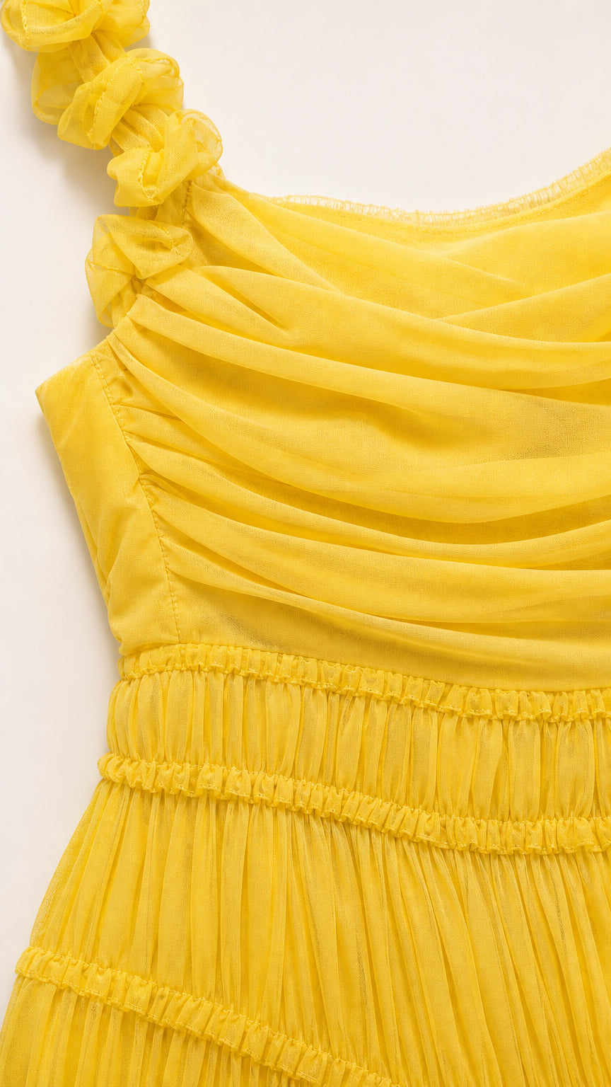 Close-up detail of yellow chiffon fabric, ruching, and floral strap