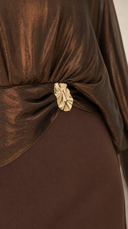 Close up view of bronze metallic shimmer drape bodice and sculptural gold buckle waist detail