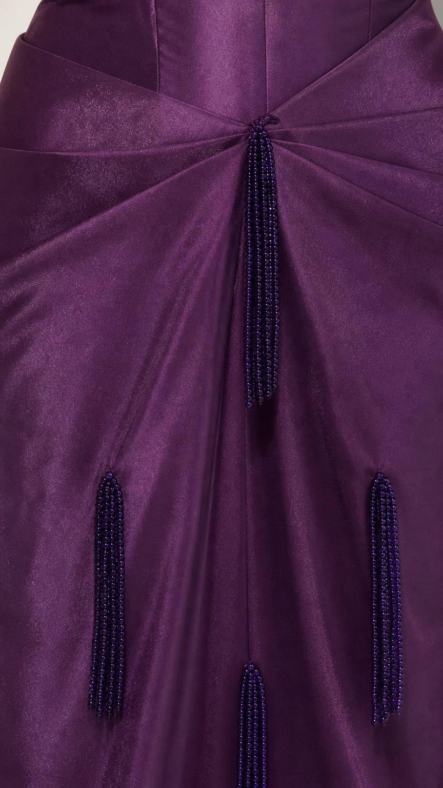 Close-up detail of purple satin fabric, gathered waist drape, and hanging beaded fringe tassels