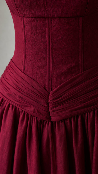 Close-up of structured bodice and pleated waist detail on burgundy gown
