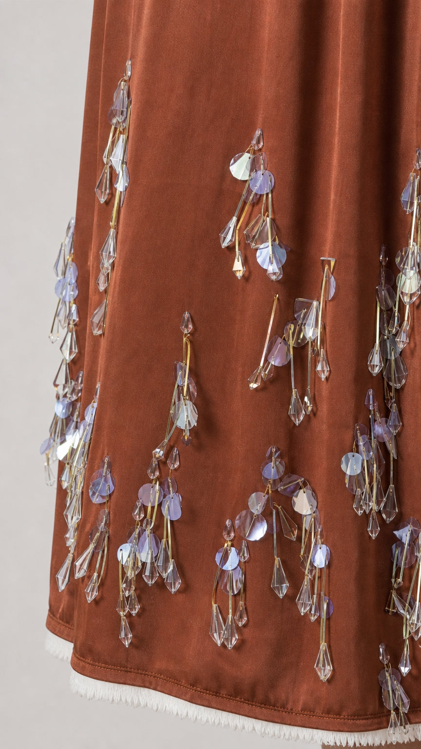 Close-up detail of hanging sequins and beads on the brown dress hem