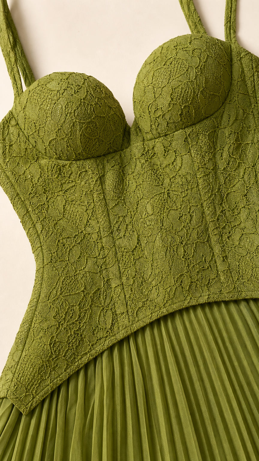 Close-up detail of structured lace bodice and pleated skirt transition in olive