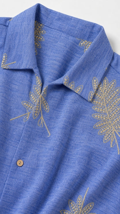 Close-up detail of blue fabric, lapel collar, buttons, and leaf print