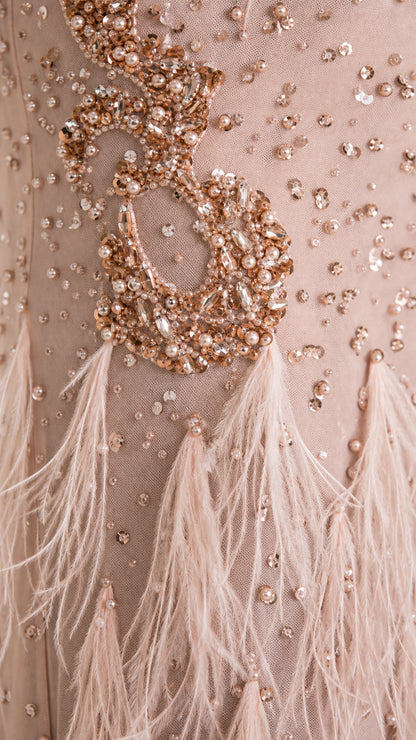 Close-up detail of blush pink dress showing pearl embellishment and feather texture