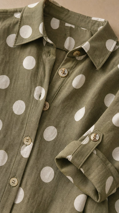 Close-up detail of collar, buttons, and roll-tab sleeve on olive polka dot dress