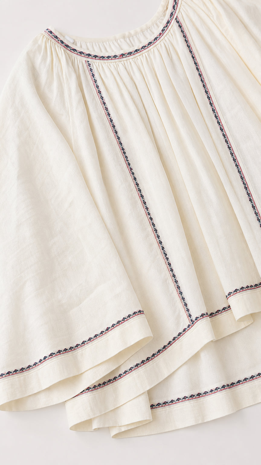 Close-up detail of embroidered geometric stitching on textured off-white fabric