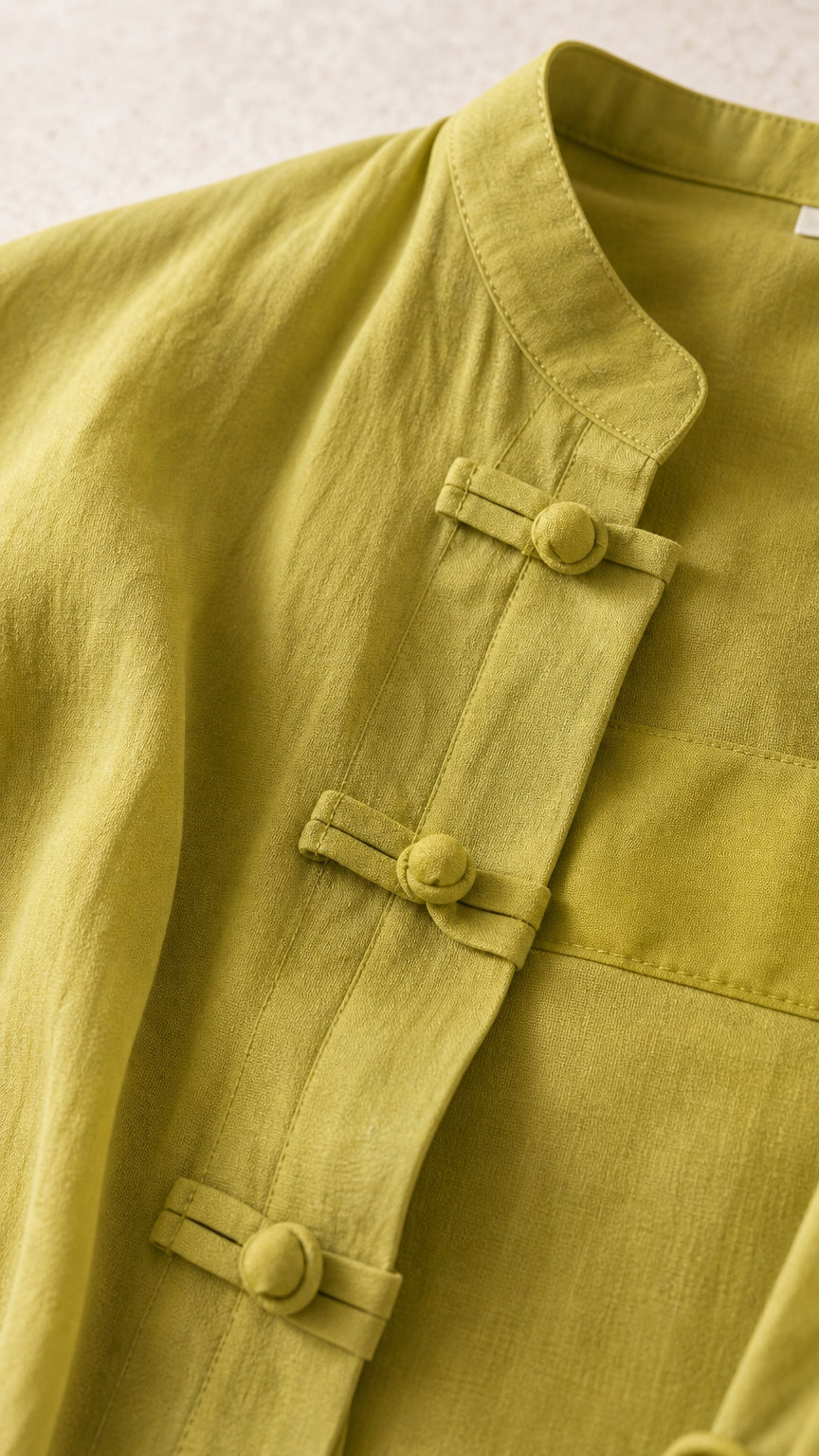 Close-up detail of mandarin collar and knot button closures on chartreuse jacket