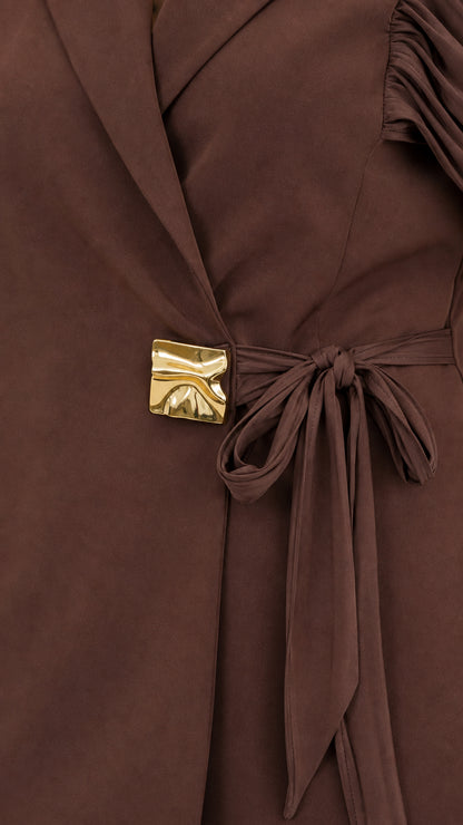 Close-up detail of blazer notched lapel, gold accent buckle, and ruched shoulder sleeve in brown