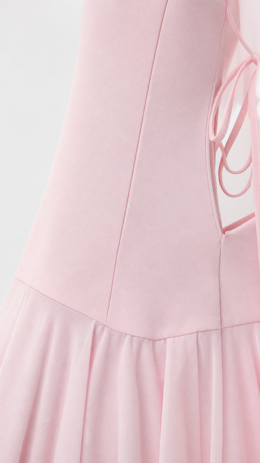 Close-up of pink dress side lace-up detail and pleated hem