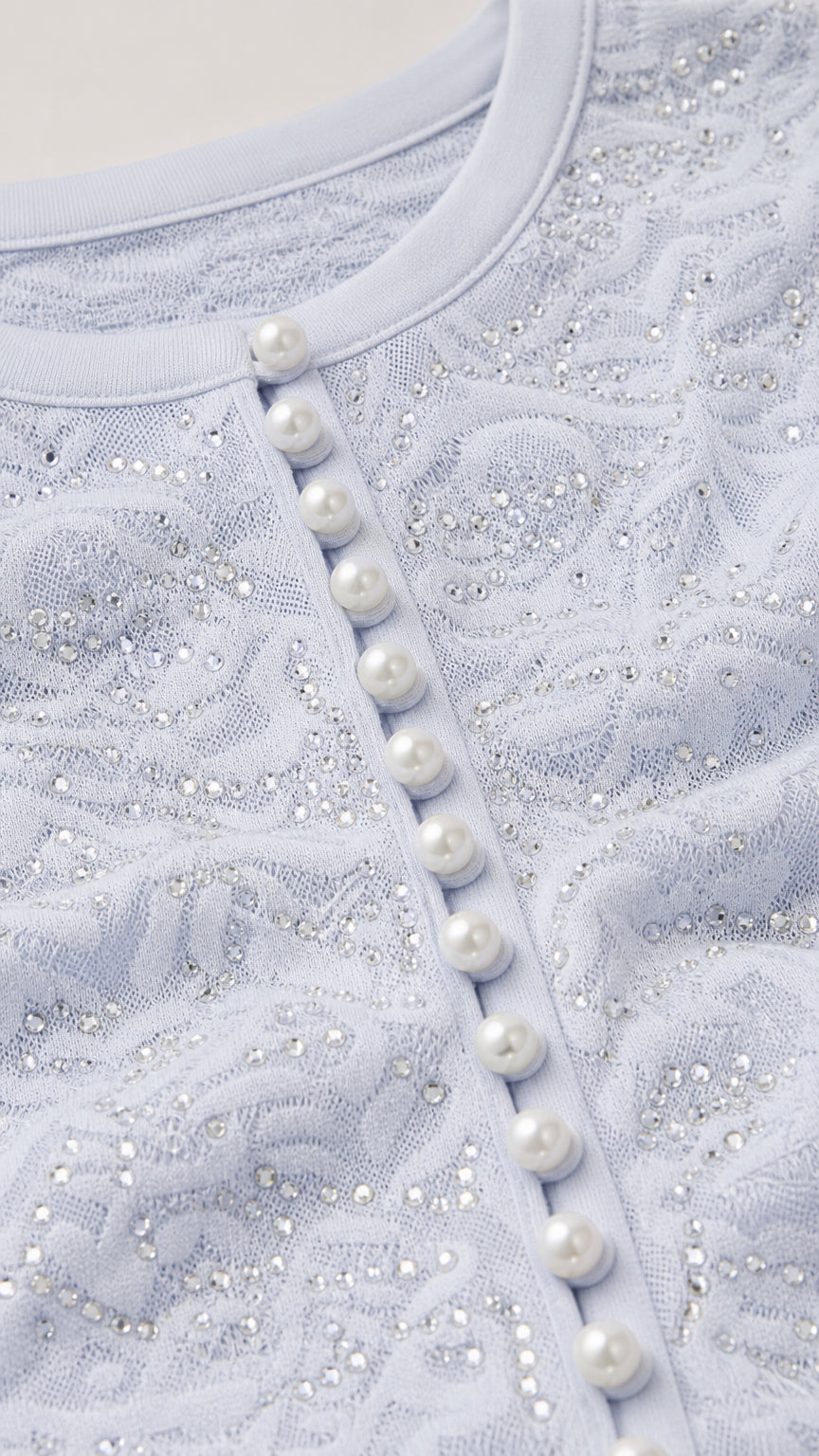 Close-up detail of pearl buttons and textured bodice on light blue dress