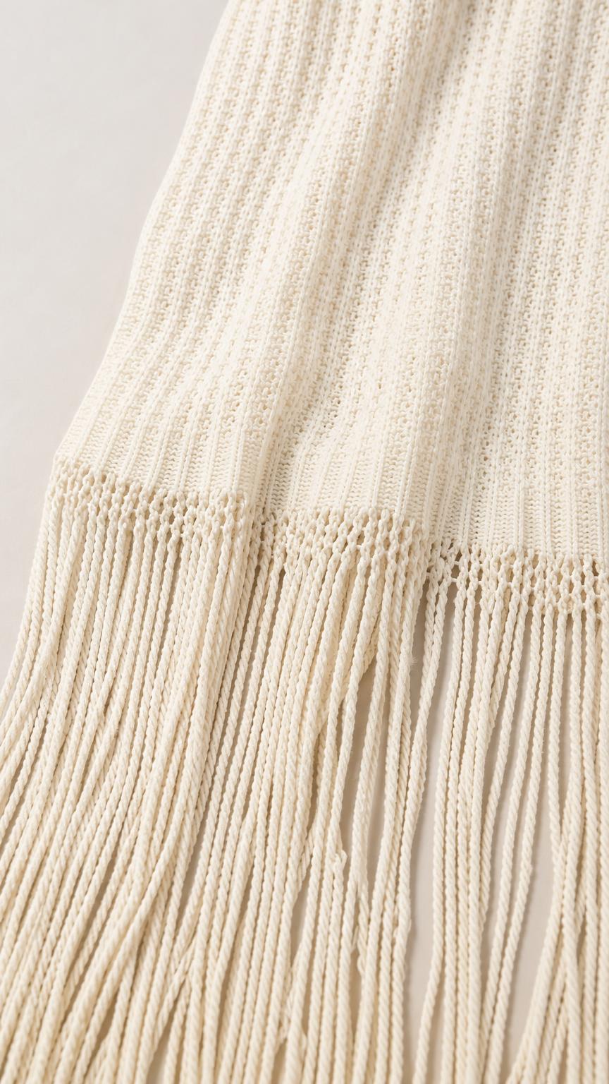 Close-up detail of the knit texture and fringe hem