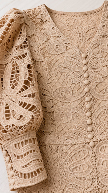 Close-up detail of crochet lace pattern, V-neck, and buttons on beige dress