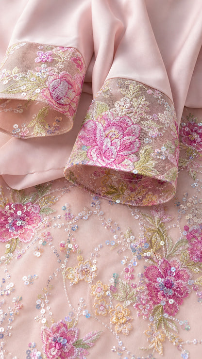 Close-up detail of pink sleeve cuff with colorful floral embroidery and sequins