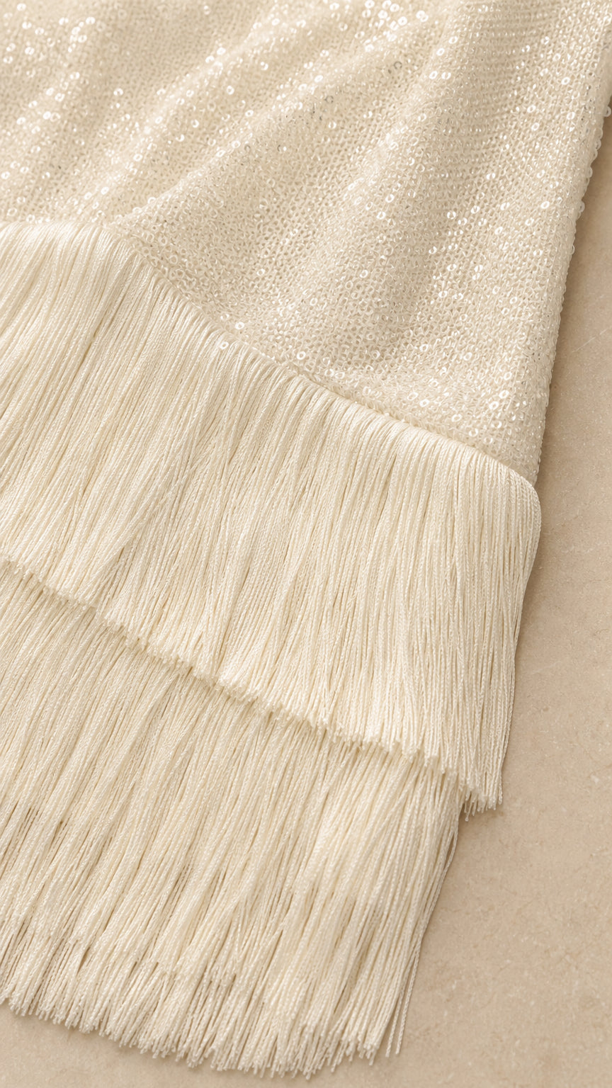 Close-up detail of white sequin fabric and multi-tier fringe hem