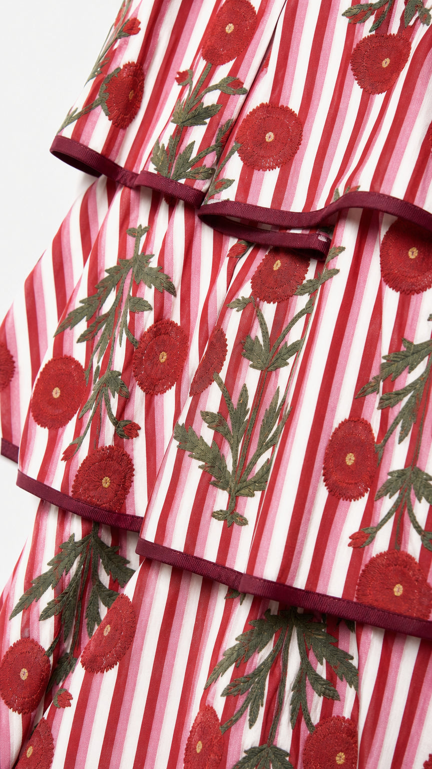 Close-up of red floral embroidery and striped ruffled hem