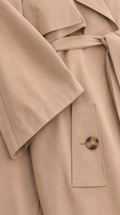 Close-up detail of smooth Camel outerwear fabric, tie belt, and buttoned pocket