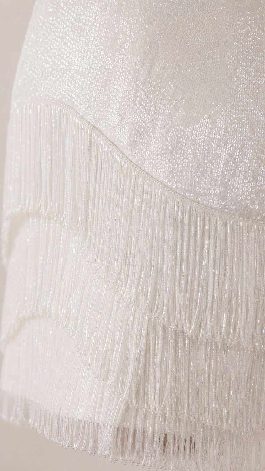 Close-up detail of white sequin fabric and fringe layers