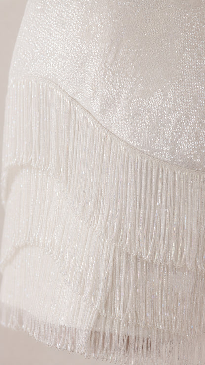 Close-up detail of white sequin fabric and fringe layers