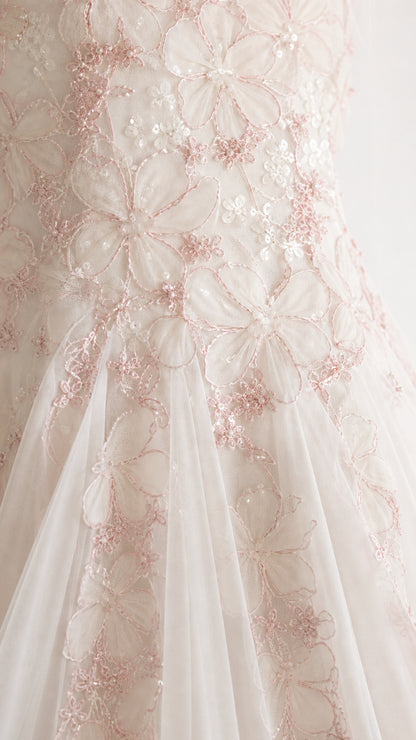 Close-up detail of delicate pink floral embroidery and shimmering sequins on tulle fabric
