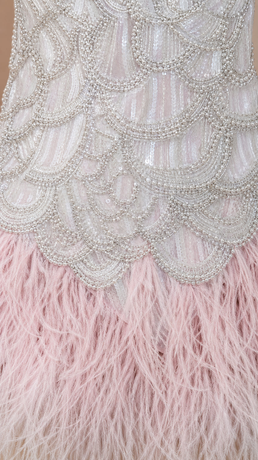 Close-up detail of silver scalloped beadwork and soft pink feather skirt texture