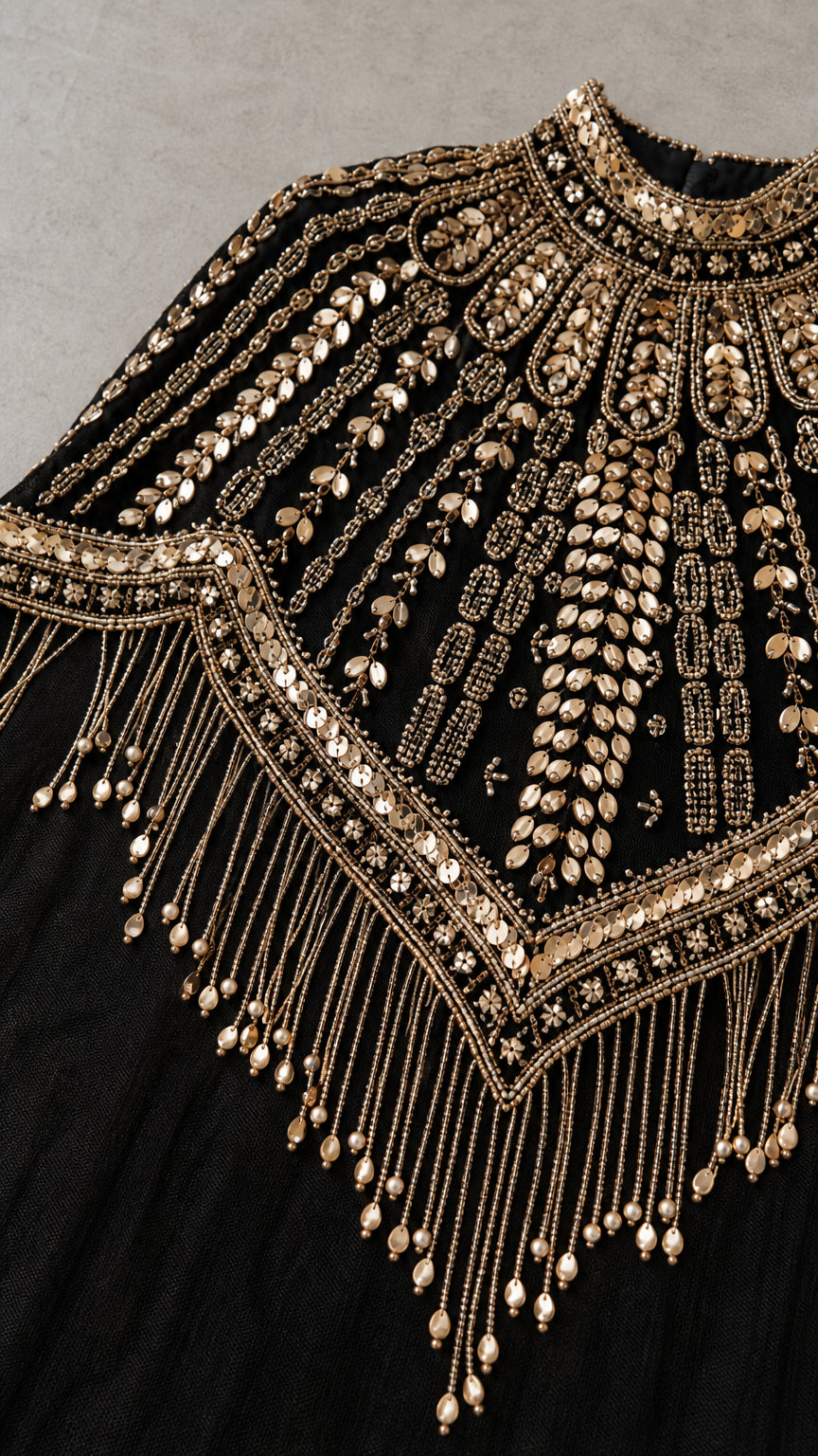 Close-up detail of intricate gold beadwork and dangling fringe on black mesh