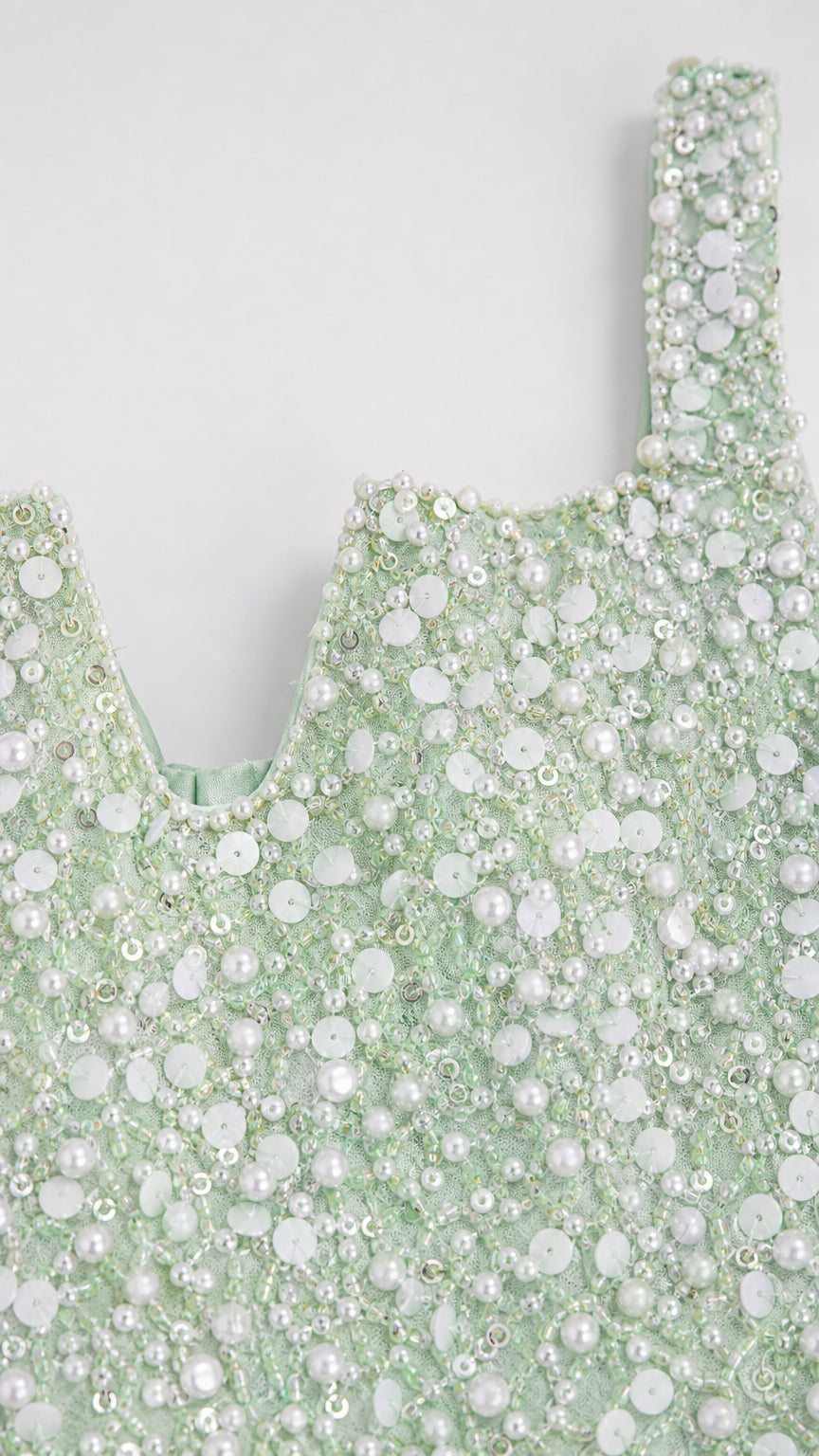 Close-up detail of mint green fabric with intricate faux pearl and sequin beading