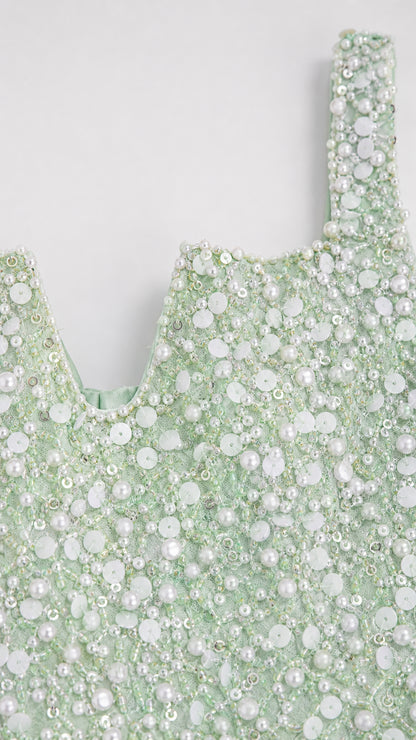 Close-up detail of mint green fabric with intricate faux pearl and sequin beading