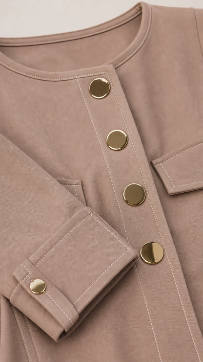 Close up of taupe jacket fabric, metallic buttons, round neckline, and cuff detailing