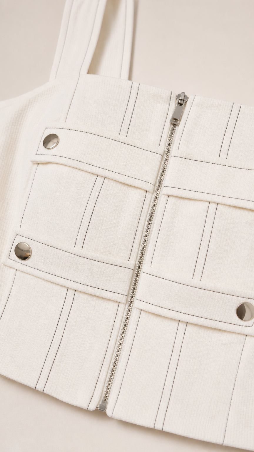 Close-up detail of white crop top featuring front zipper and contrast stitching