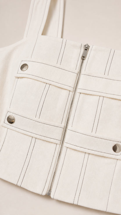 Close-up detail of white crop top featuring front zipper and contrast stitching