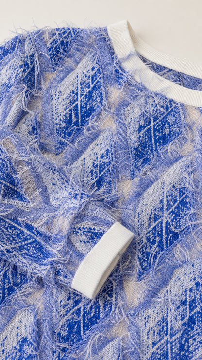 Close-up of blue textured knit fabric and contrast white ribbed trim