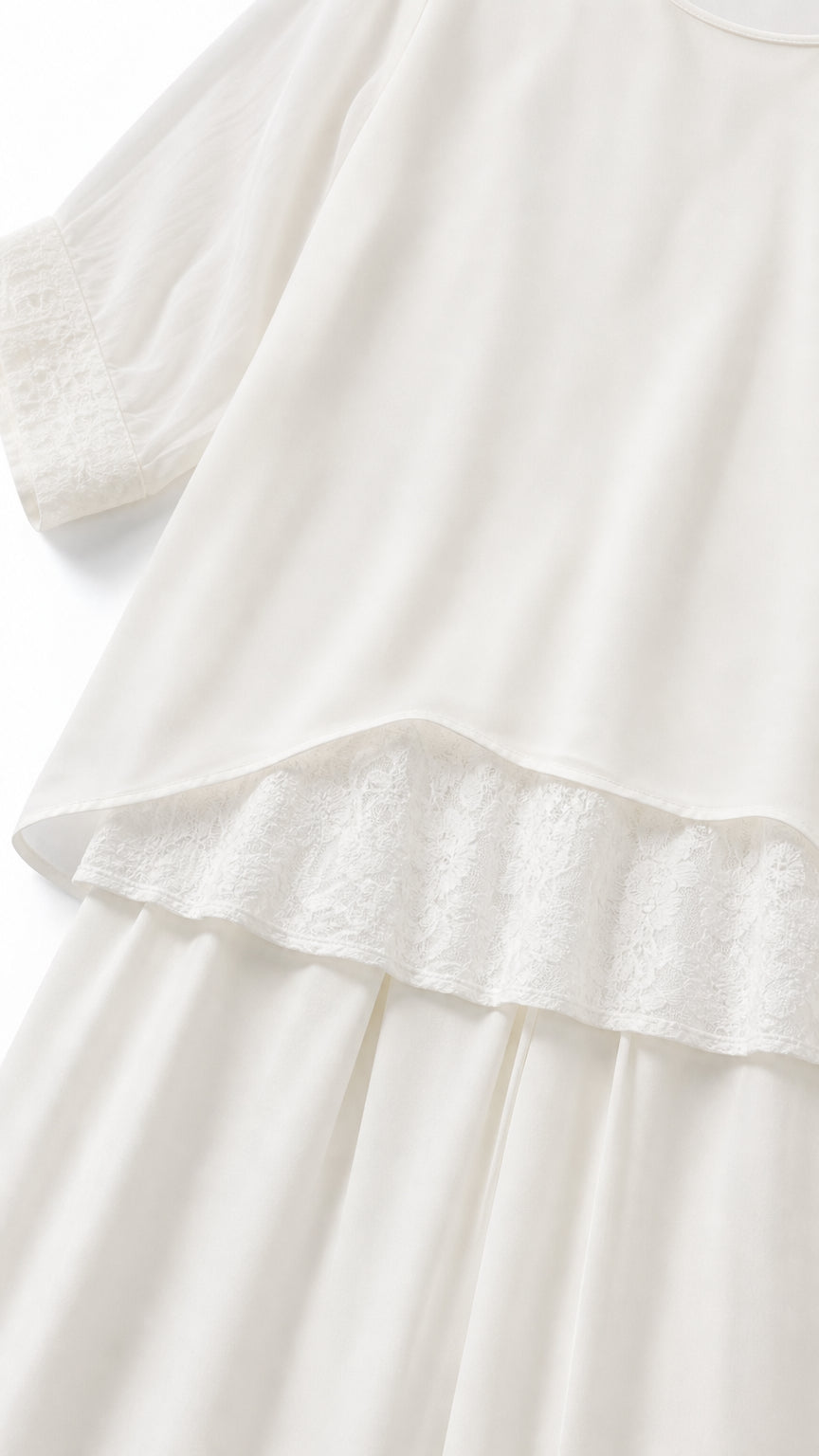 Close-up of white tunic hem with delicate lace trim