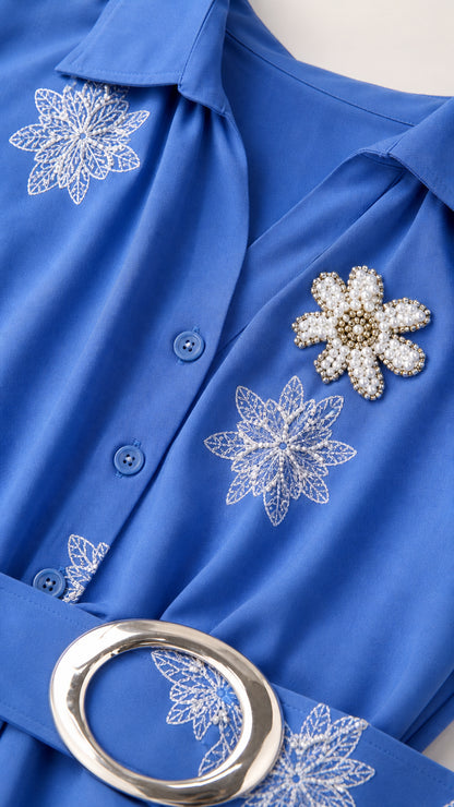 Close up of collar, buttons, embroidery and belt buckle on blue dress