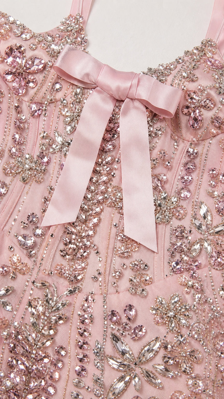 Close-up detail of crystal beading, sequin embroidery, and satin bow accent on gown bodice