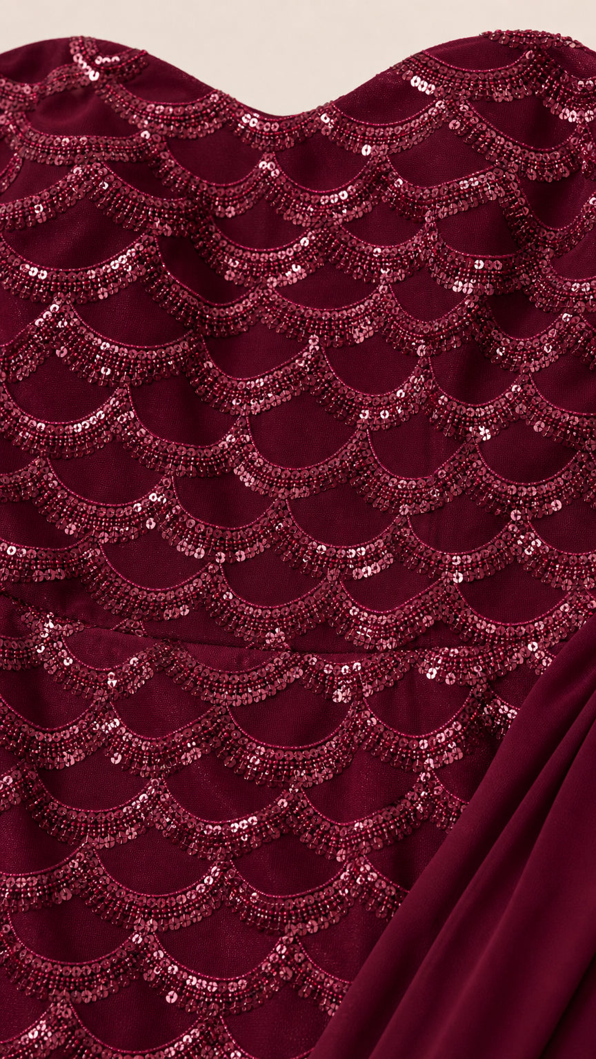 Close-up of burgundy scalloped sequin fabric and draped cape material