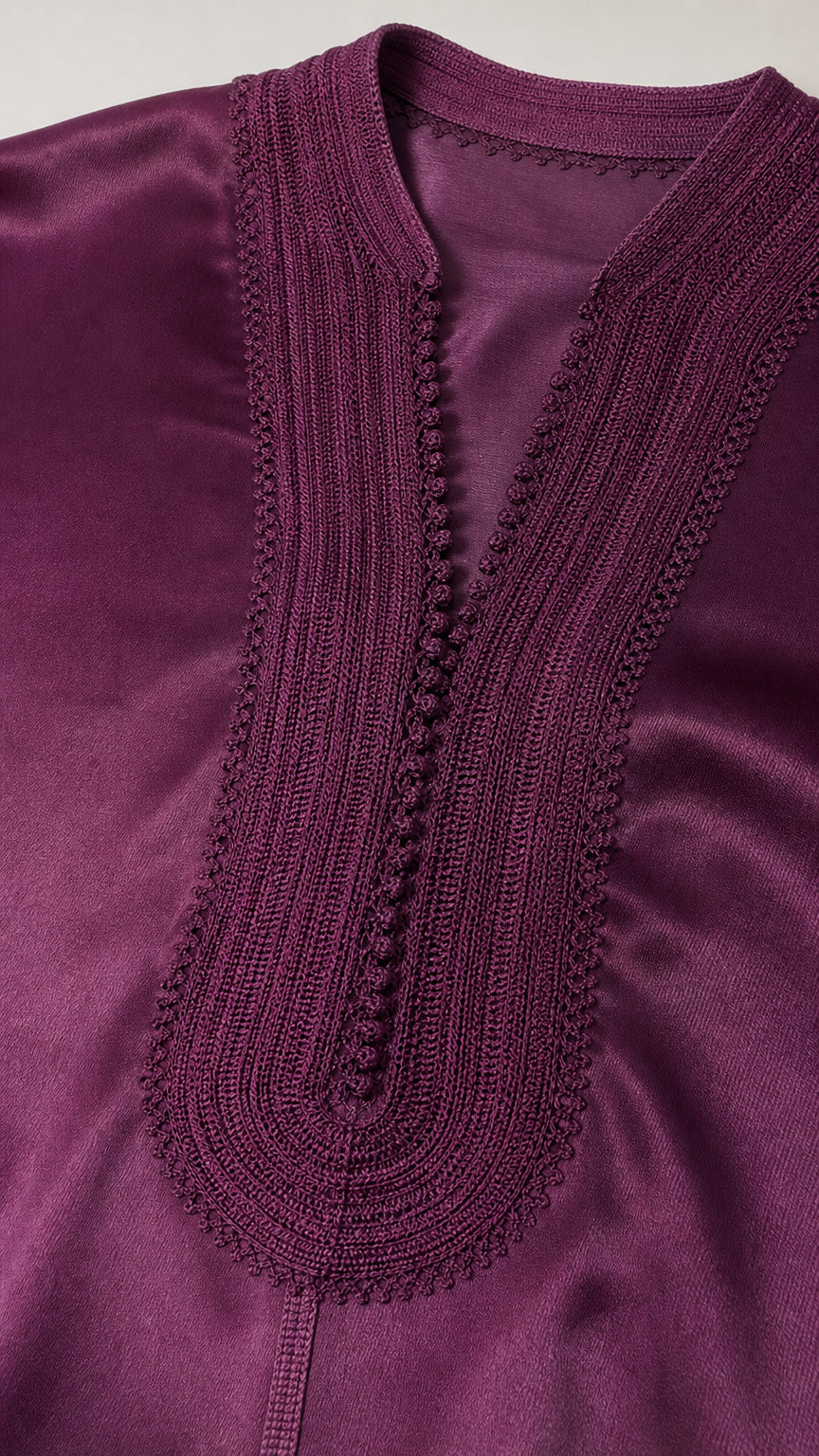 Close up detail of intricate embroidered trim on deep purple satin split neckline