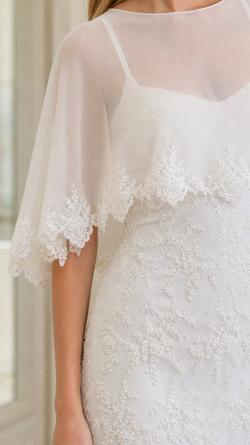 Close-up detail of sheer capelet lace trim and floral embroidery on white dress