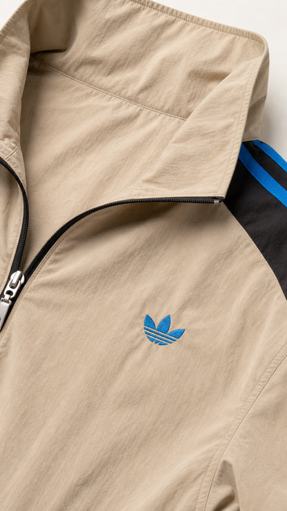 Close-up detail of khaki tan stand-collar jacket zipper and embroidered logo