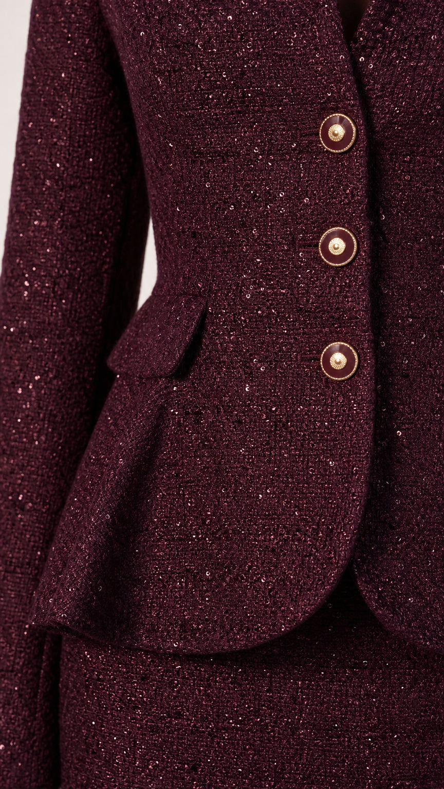 Close-up detail of textured burgundy tweed fabric, waist flap, and round buttons