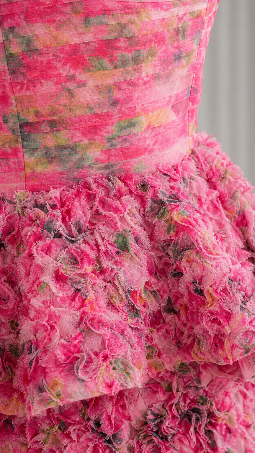 Close-up detail of textured floral fabric and ruffle tiers on pink dress