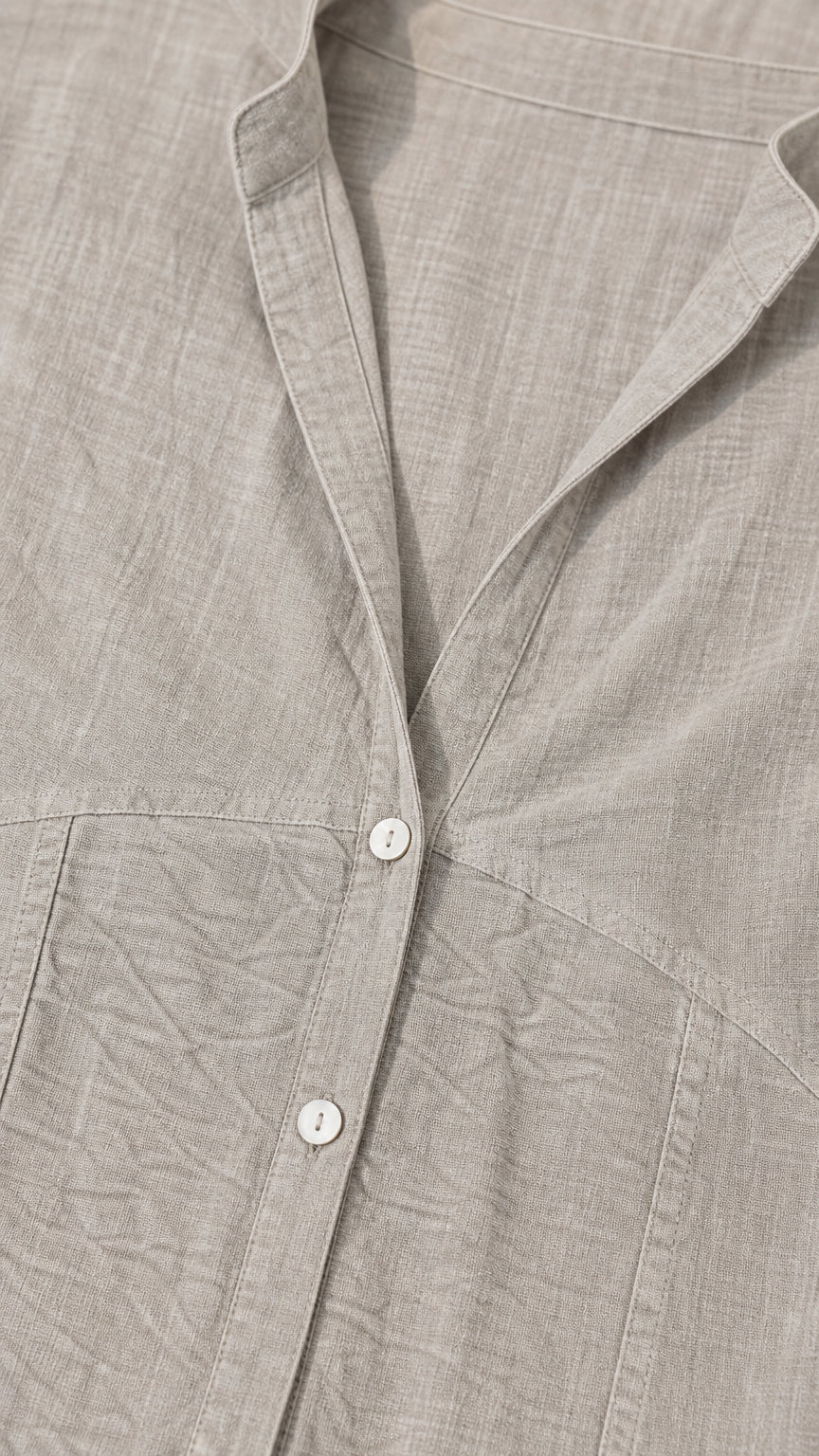 Close-up detail of grey textured fabric, buttons, and collar