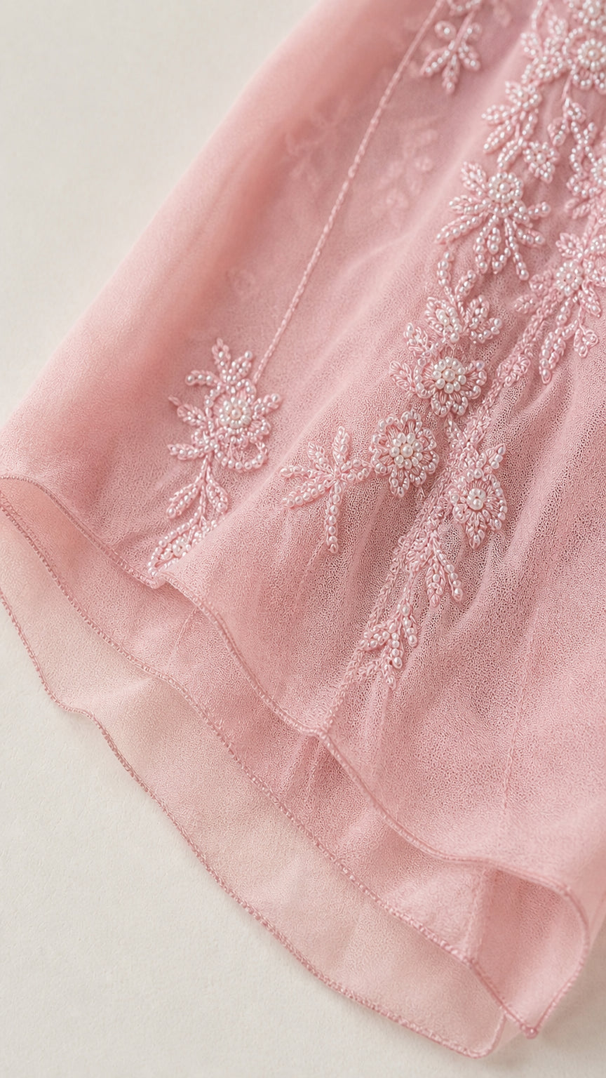Close up view of floral embroidery and beading detail on the pink skirt hem