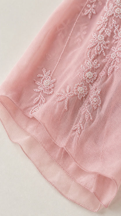 Close up view of floral embroidery and beading detail on the pink skirt hem