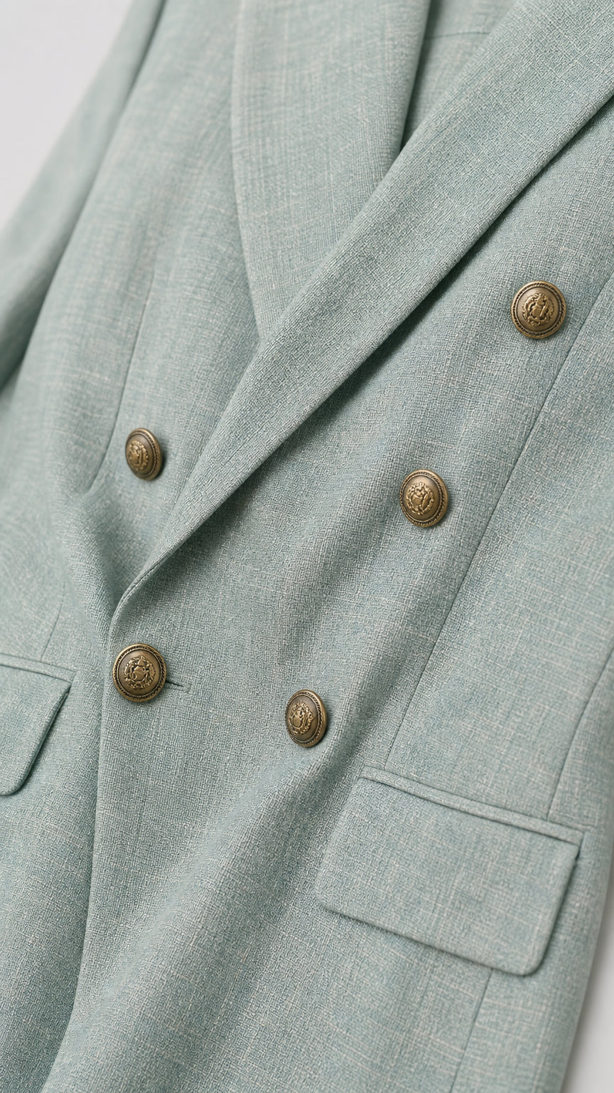 Close-up detail of blazer buttons and textured fabric in sage green