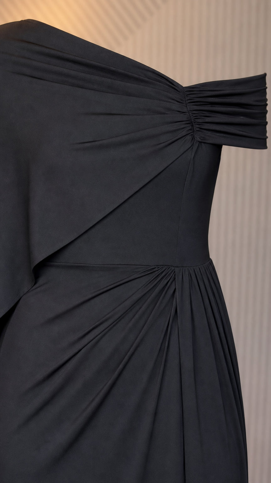Close up of shoulder drape and ruched waist on black dress