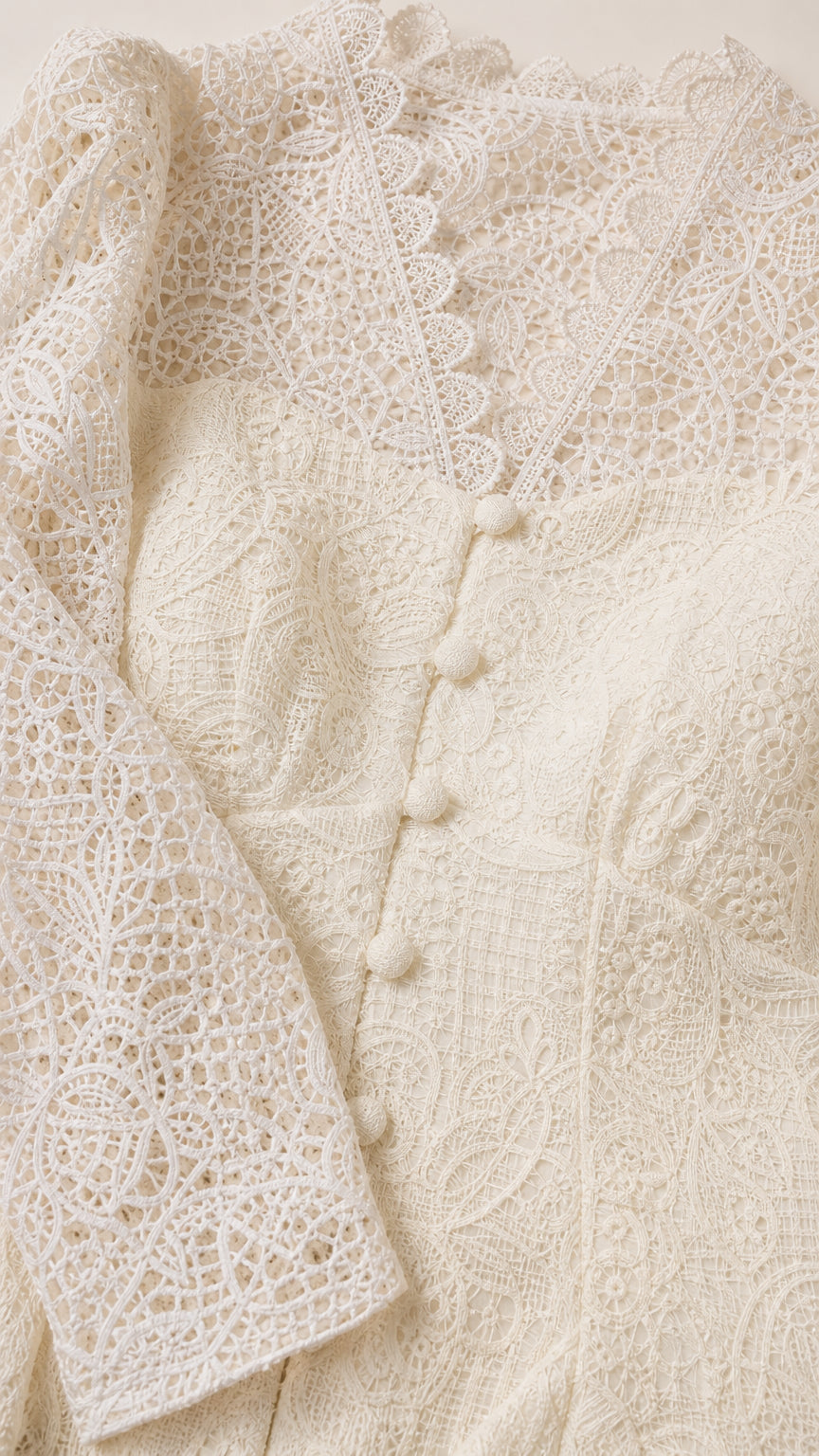 Close-up detail of ivory lace fabric, scalloped neckline, and button front placket