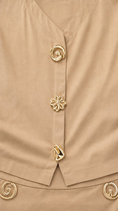 Close-up detail of sculptural gold-tone buttons on khaki V-neck blouse and waistband