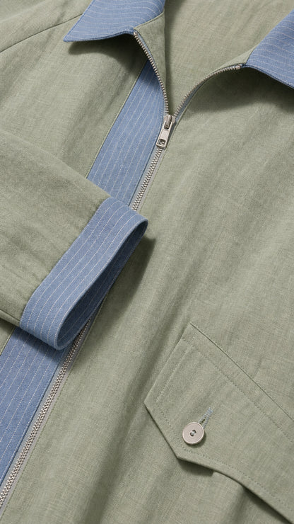 Close-up detail of zipper neckline, collar, and buttoned pocket flap on sage green fabric