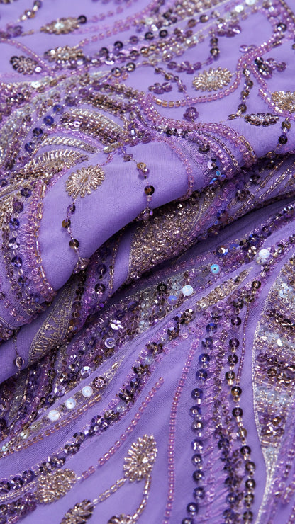 Close-up detail of intricate purple and silver sequin and bead embroidery on mesh fabric