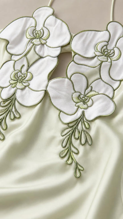 Close-up detail of white and green 3D floral appliques on satin bodice